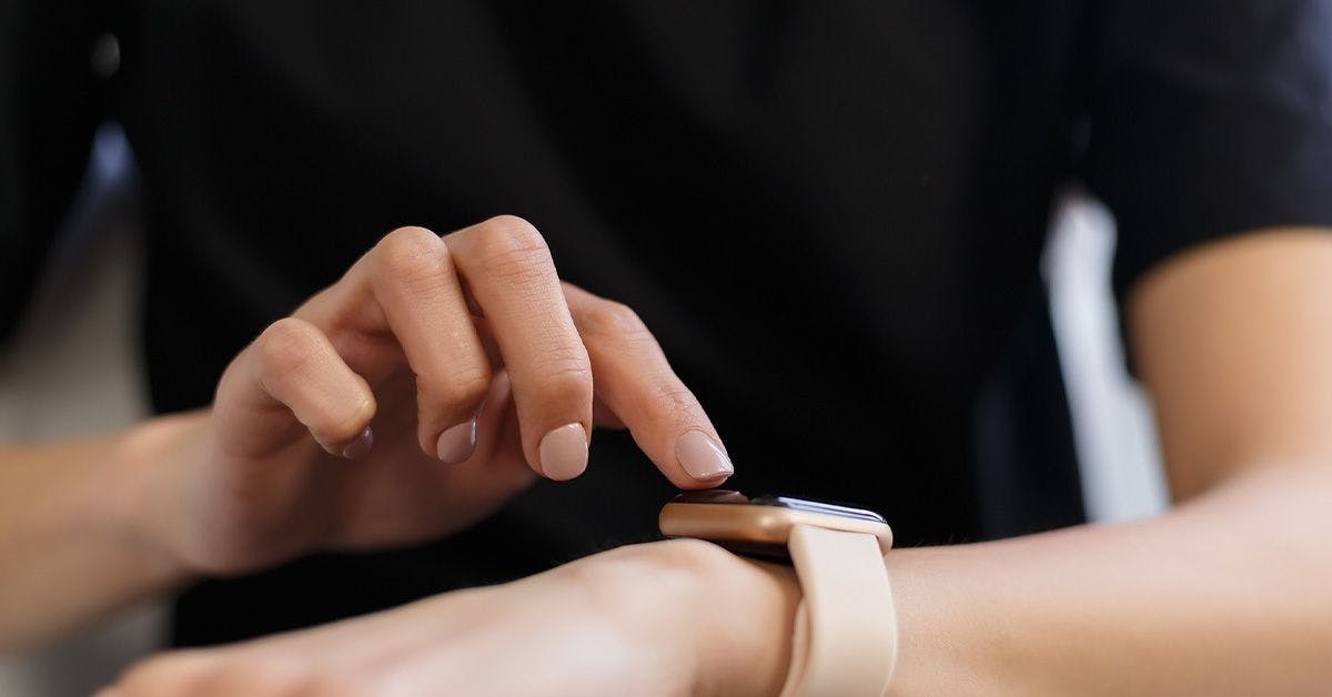 A person wearing a black shirt interacts with a smartwatch on their wrist, touching its screen with their other hand.