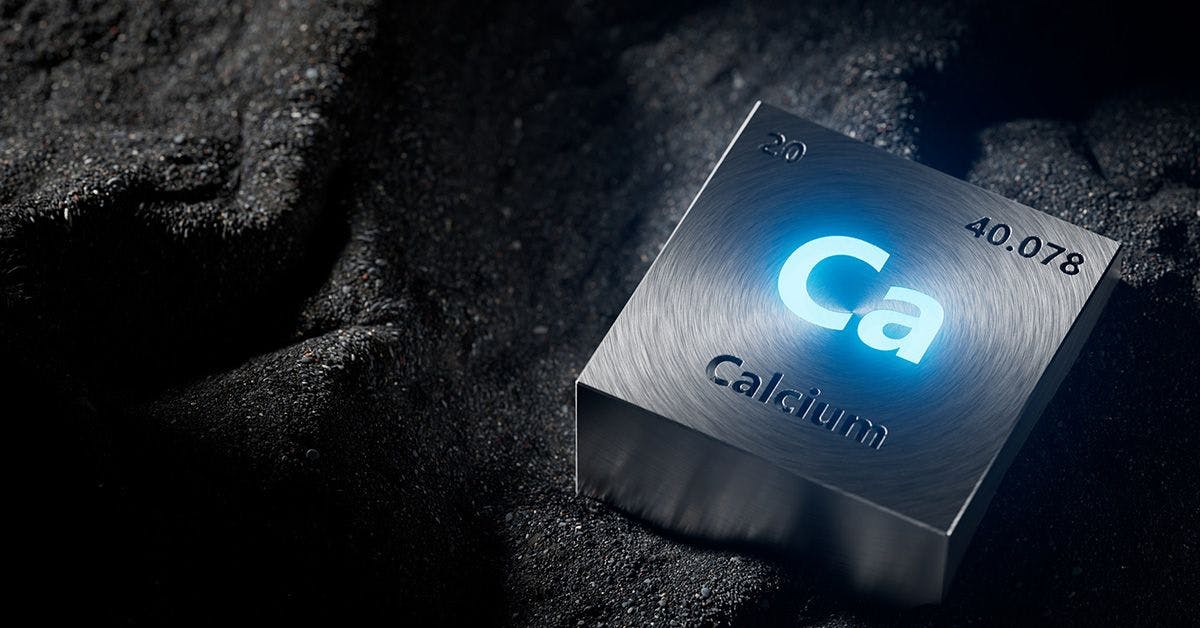 A metallic cube with "Ca" symbol, atomic number 20, and atomic mass 40.078 represents the element Calcium, placed on a dark, textured surface.