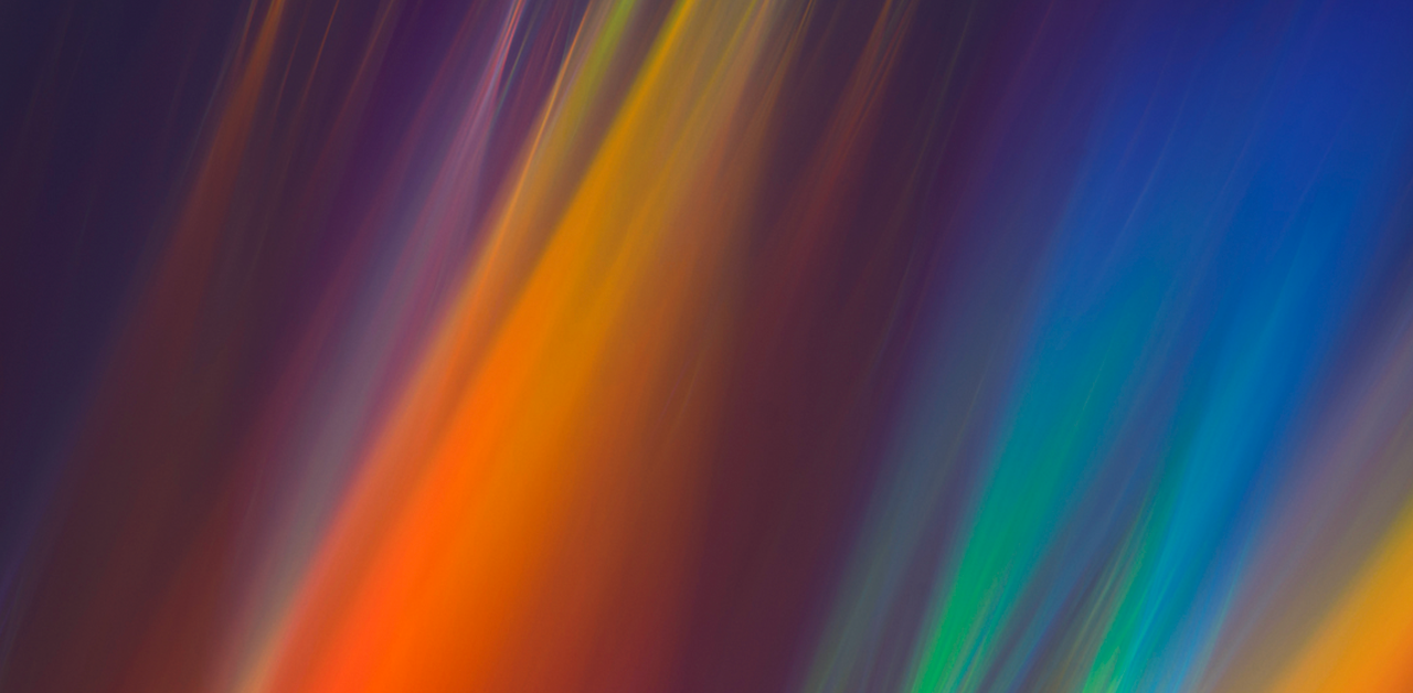An abstract image featuring vibrant streaks of colors, including red, orange, yellow, green, and blue, on a dark background.