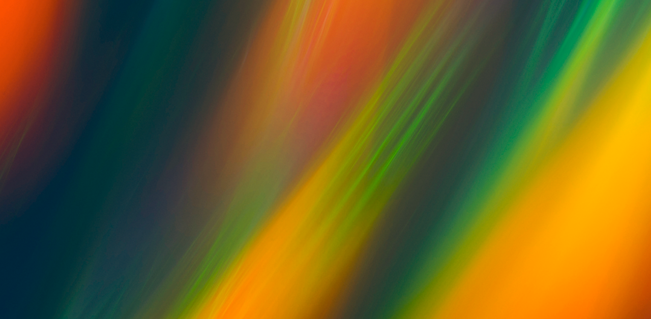 Abstract image featuring vibrant streaks of orange, green, red, and blue, blending together with a blurred, flowing effect.