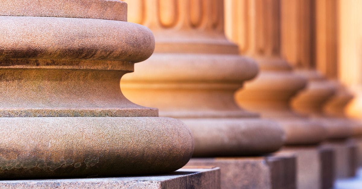 Close-up of the bases of stone columns lined up in sequence, showcasing their detailed carved design and smooth, rounded surface.