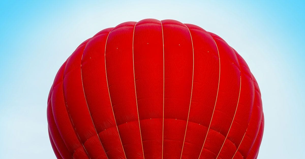 A red hot air balloon against a blue sky.
