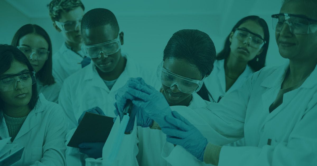 A group of scientists in lab coats and safety goggles are working together in a laboratory.