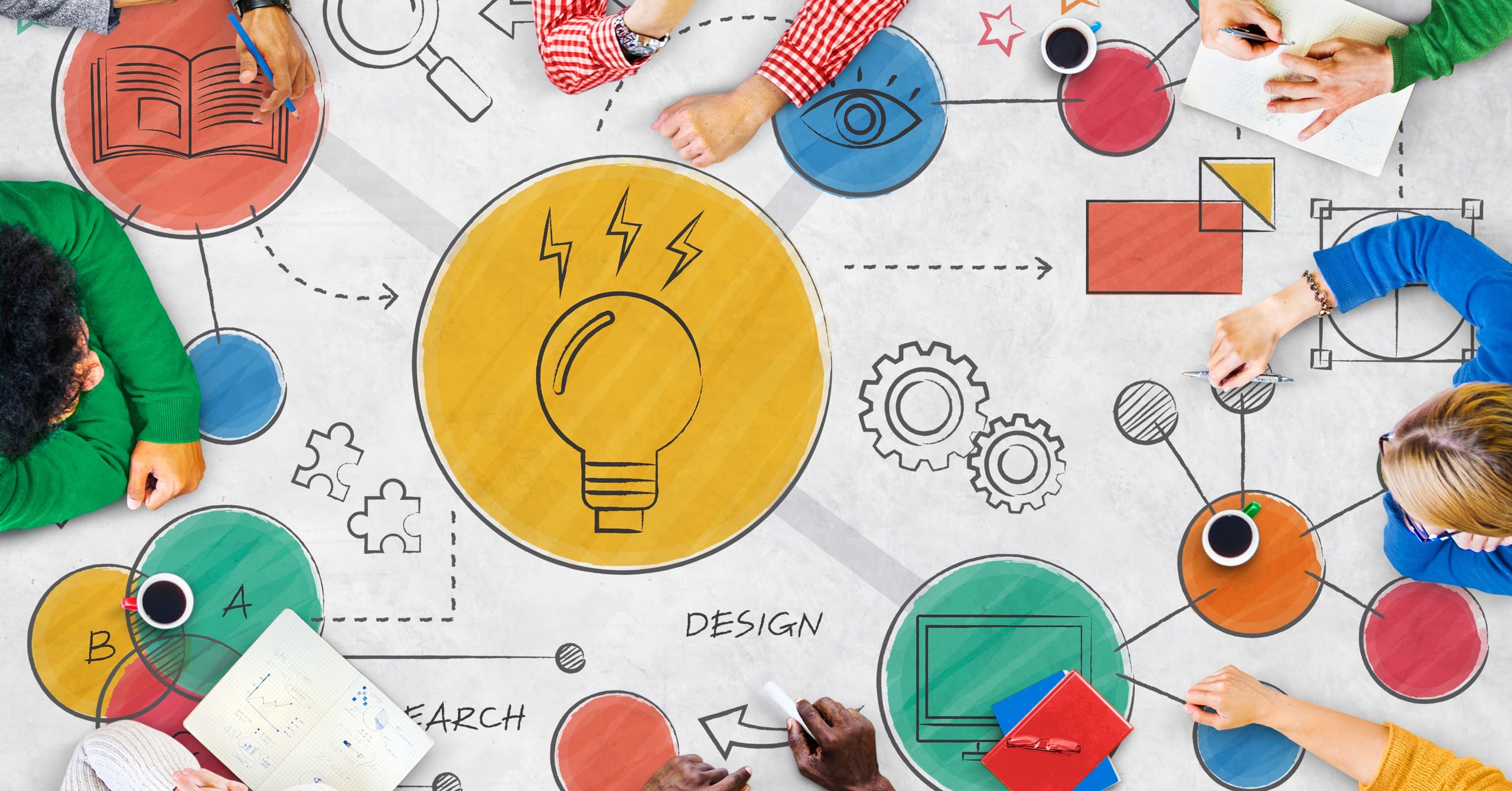 A group of people sitting around a table with a light bulb.