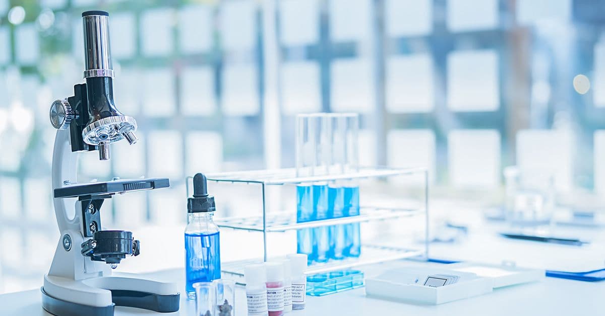 Laboratory setting with a microscope and test tubes containing blue solutions.