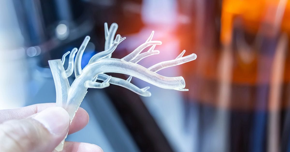 A hand with object in shape of a medically accurate human blood vessel printed on a 3d printer.