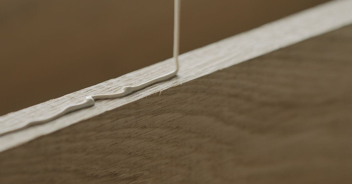 A line of wood glue being poured onto an oak board.