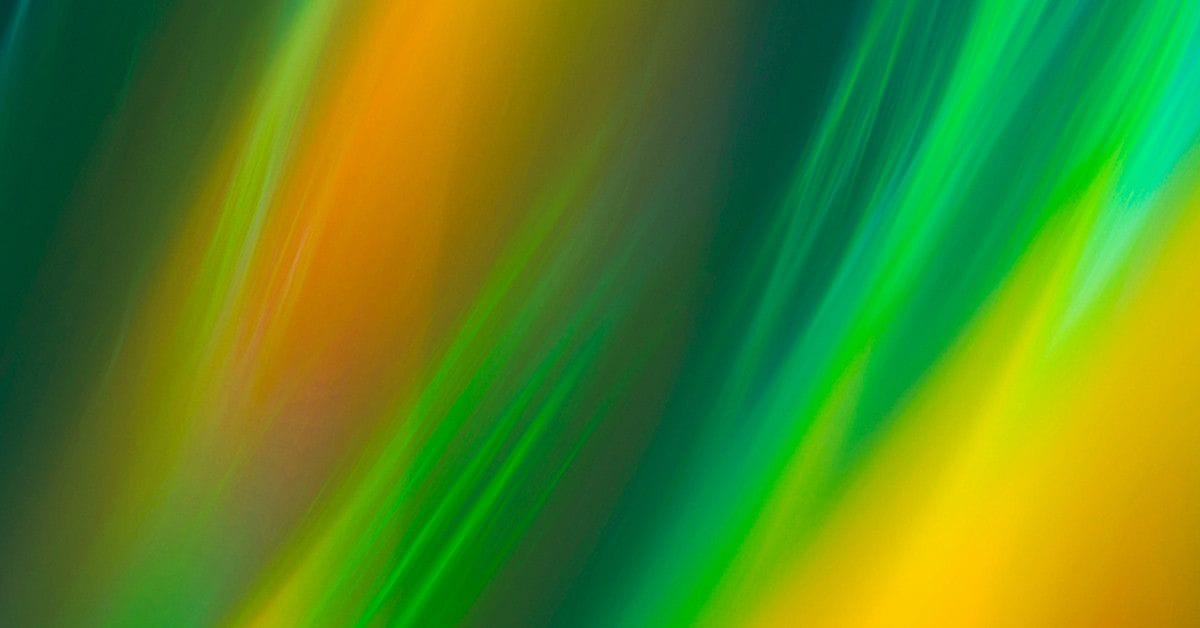 Abstract image featuring vibrant streaks of orange, green, and yellow, blending together with a blurred, flowing effect.