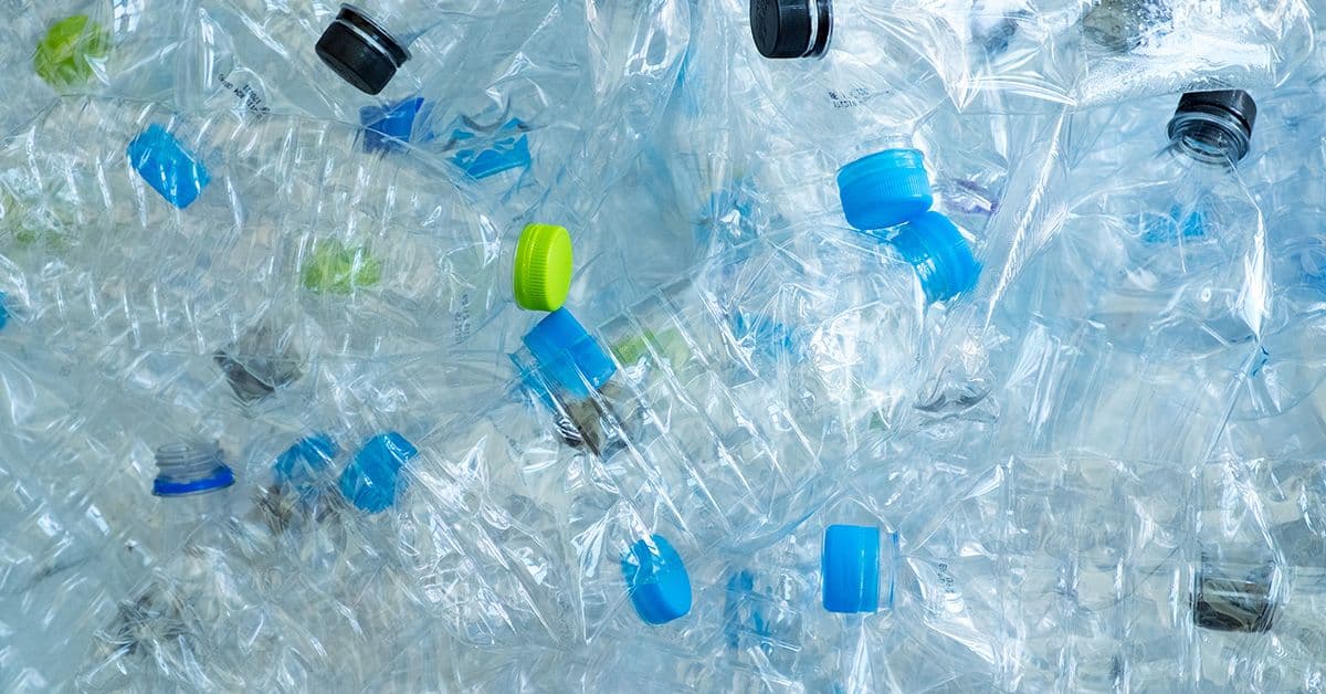 A pile of used plastic water and beverage bottles.