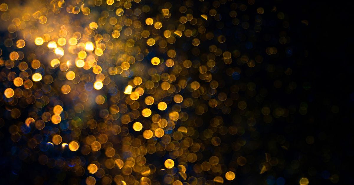 Out-of-focus bokeh effect with warm golden lights scattered against a dark background, creating an abstract pattern.