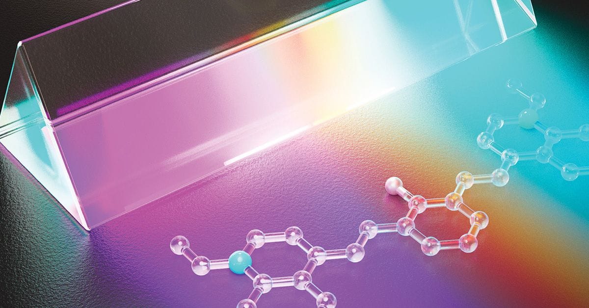 A transparent prism casting a rainbow gradient on a dark surface, with a molecular structure made of clear spheres and rods arranged in a chain pattern beneath the colorful light.