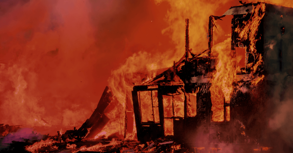 A house engulfed in flames, surrounded by thick smoke, with fiery orange and red hues illuminating the scene.