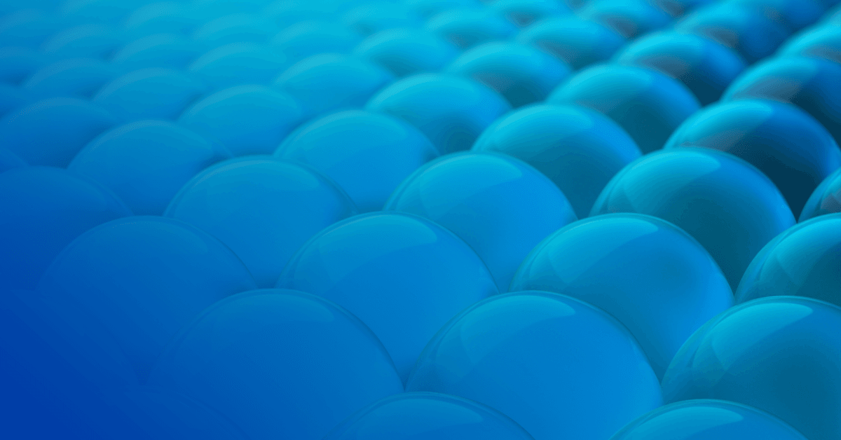 A close-up of glossy, rounded blue spheres arranged in a wave-like pattern, creating a vibrant and droplet-like surface.