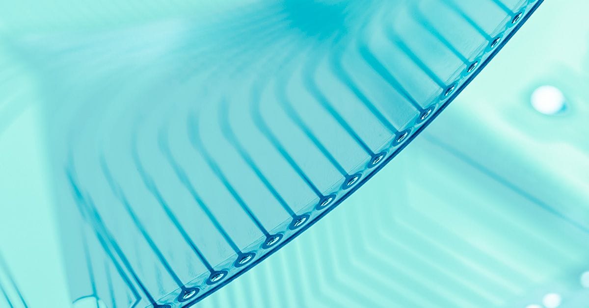 Close-up view of a translucent blue plastic object with a ribbed pattern and circular perforations on the edge, possibly part of a container or cover.