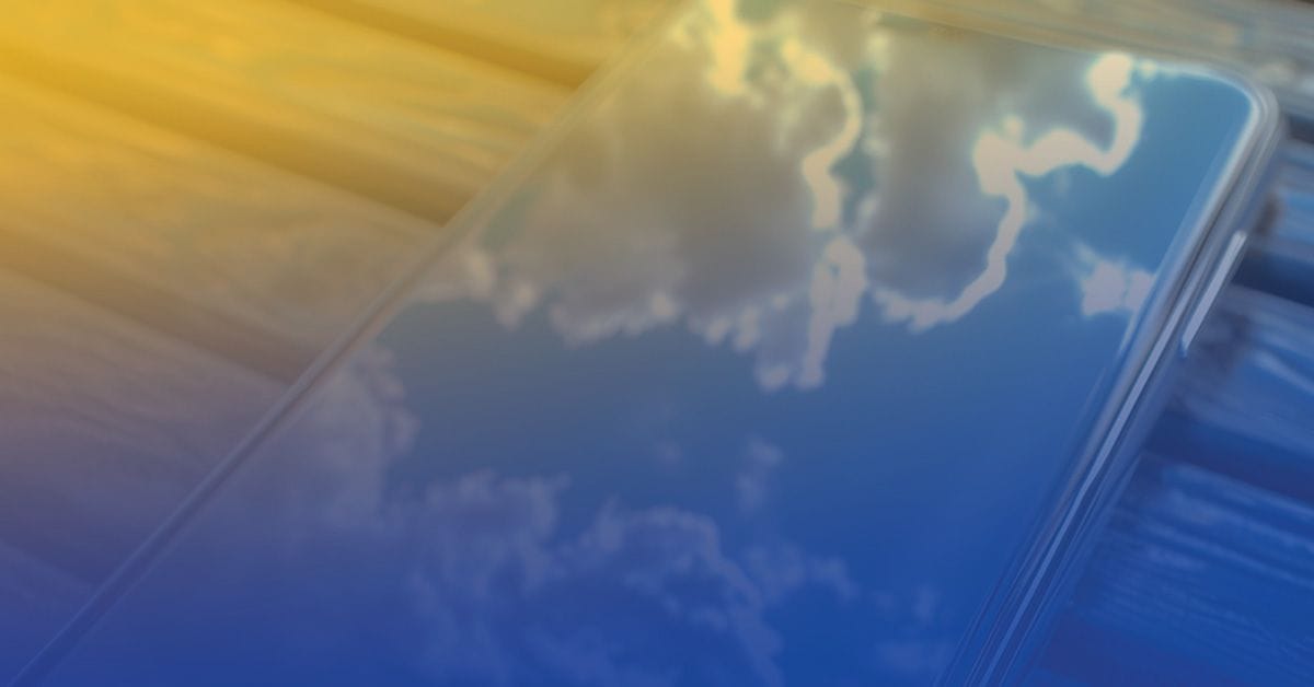 A smartphone with its screen reflecting blue sky and clouds, placed on a wooden surface.