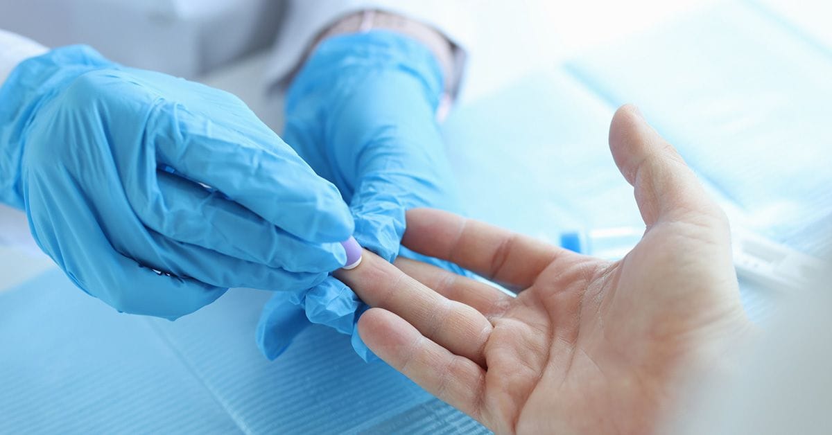 Close-up of nurse lab technician in gloves, using painless scarifier to prick finger of patient. Blood analysis, group determination and medicine concept