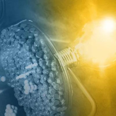 A light bulb filled with small, clear spheres, illuminated and casting a bright glow.