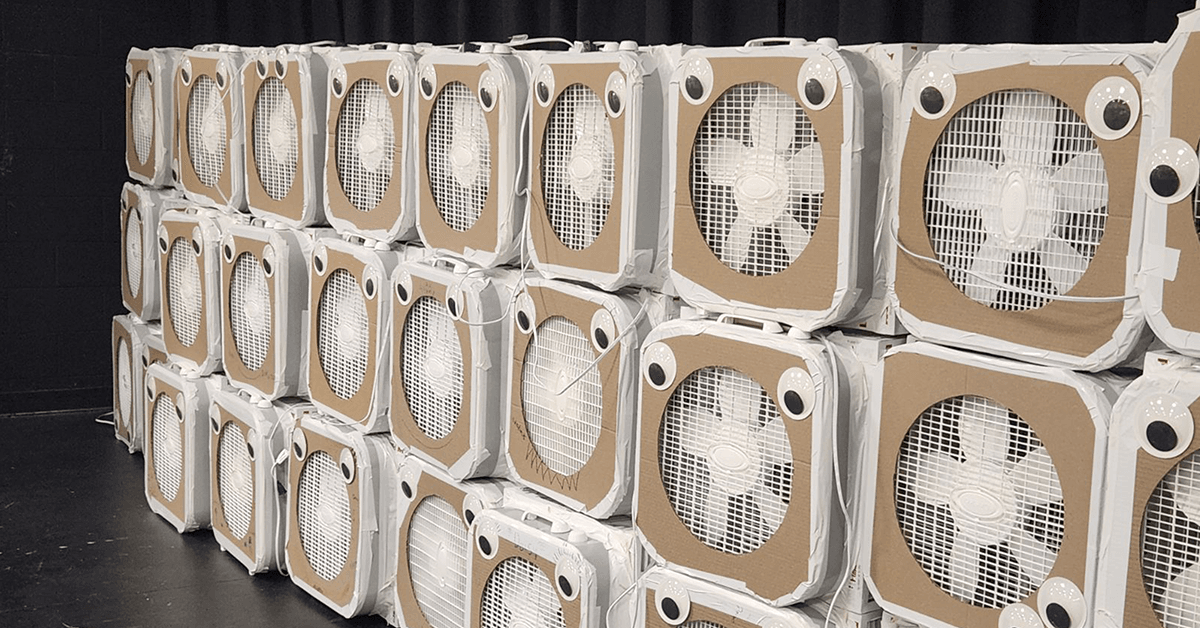 Dozens of homemade Corsi-Rosenthal Box air purifiers, each made from a white box fan mounted on a cardboard filter housing, stacked in rows.