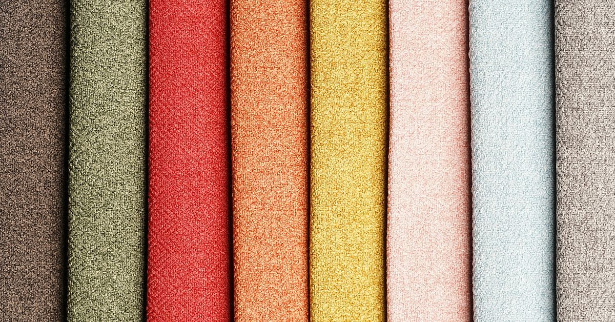 A collection of vibrant textile swatches in shades of brown, green, red, orange, yellow, pink, blue, and gray, showcasing various textures.