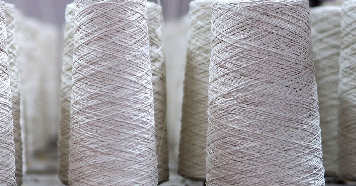 Close-up of several spools of white thread arranged vertically.