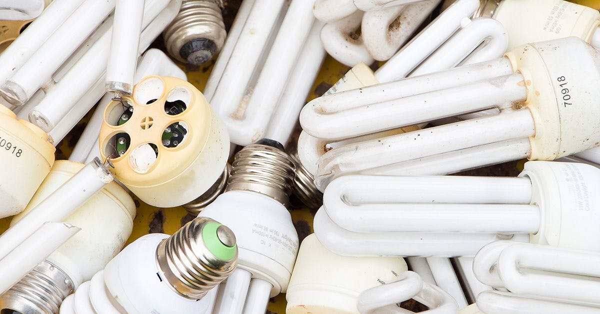 A collection of various discarded compact fluorescent lightbulbs and tube lights, showing assorted shapes and sizes.