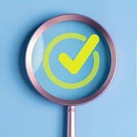 A digital illustration of a magnifying glass hovering over a bright green circled check mark.