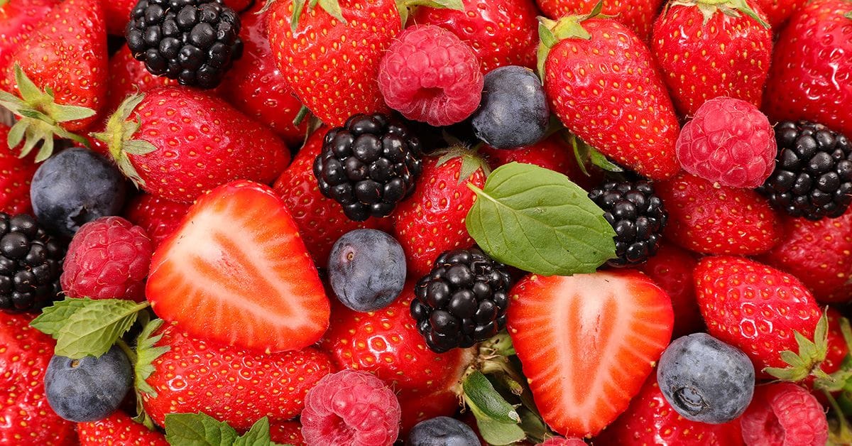 A colorful assortment of fresh strawberries, raspberries, blackberries, and blueberries, garnished with mint leaves.
