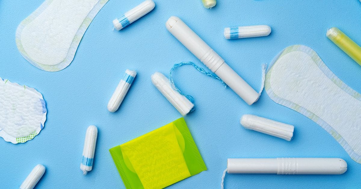 A collection of feminine hygiene products, including pads and tampons, on a blue background