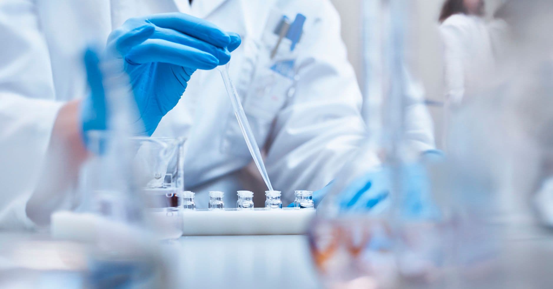 A chemist at Work in a Medical Laboratory, filing vials with a dropper
