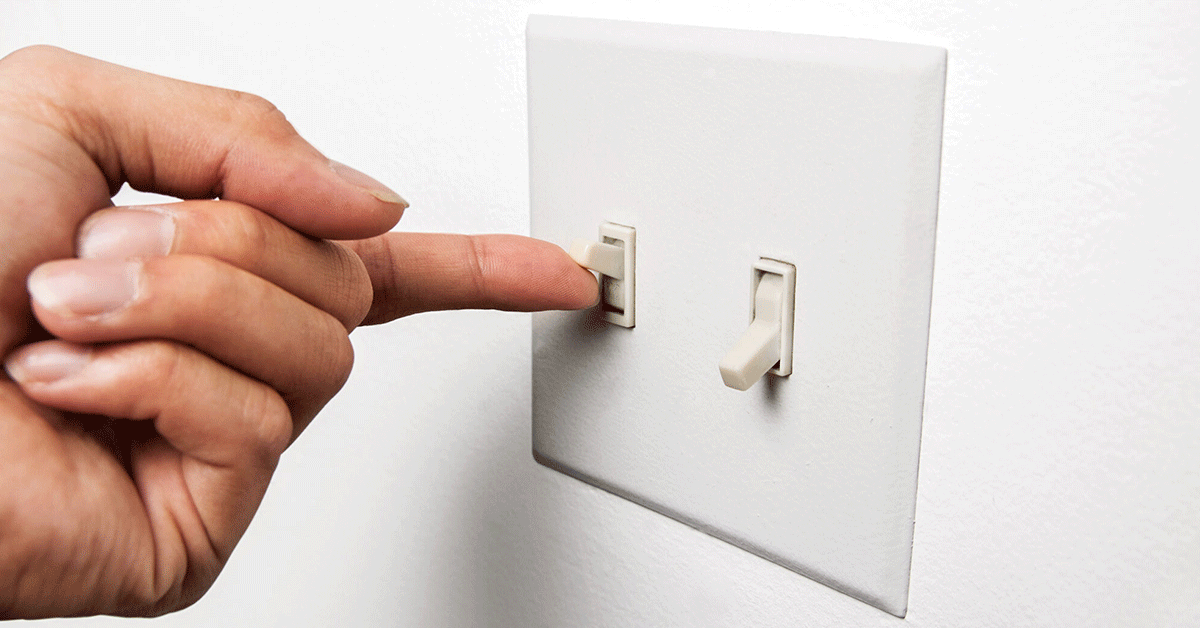 a hand turning a light switch on