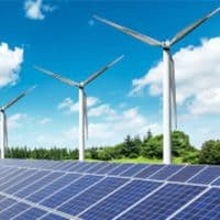 Solar panels with wind turbines in the background.