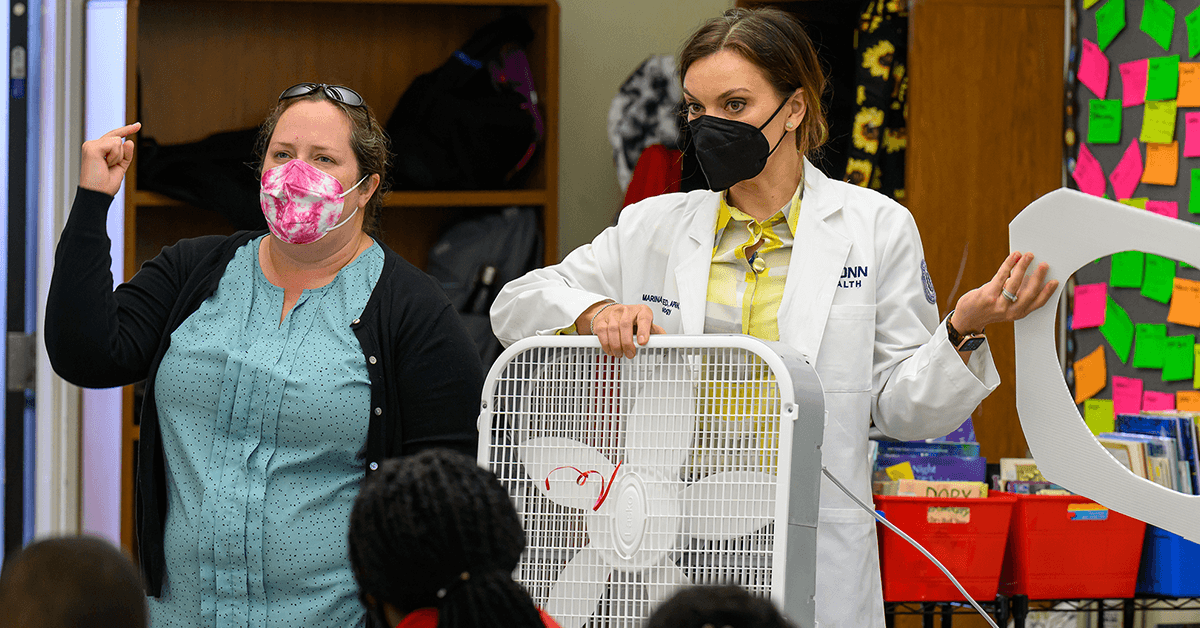 Kristina Wagstrom (left) and Marina Creed present a DIY Corsi-Rosenthal Box air filter during a classroom visit.