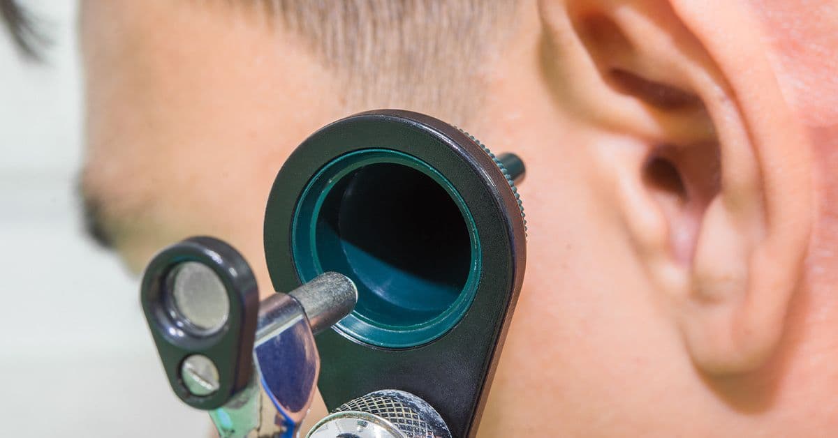 A close-up of a human ear, showcasing the intricate details of the outer ear structure against a light background.