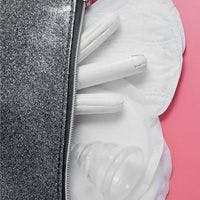A zipper dividing two contrasting textures with feminine hygiene products on a pink background.