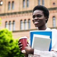 A woman holding a cup of coffee in front of a building.