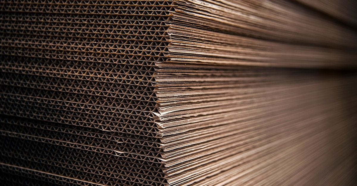 A pile of stacked, collapsed corrugated cardboard boxes.