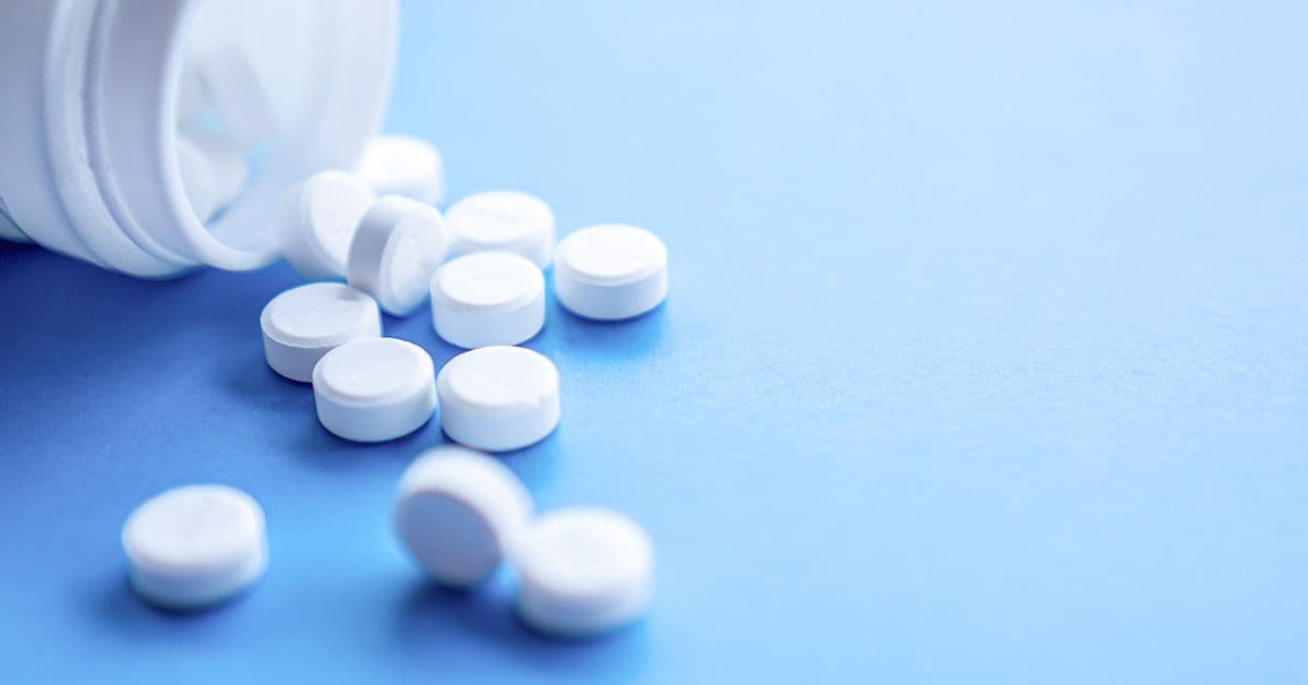 A bottle of unlabeled, generic white tablet pills on a blue background