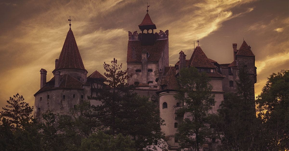 A castle with turrets sitting on top of a hill.