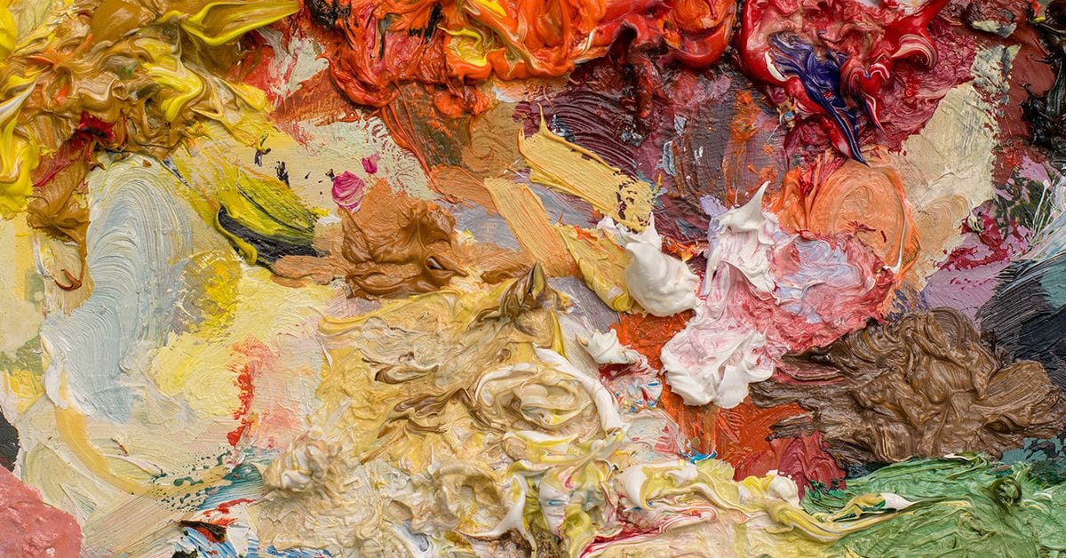 A smattering of bright oil paints mixed together on an artist's palette.