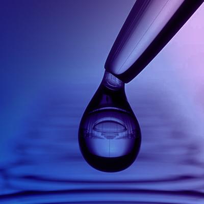 A close-up of a droplet hanging from a pipette against a soft purple gradient background, reflecting circular ripples below.