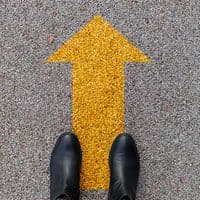 A person's feet standing next to a yellow arrow.