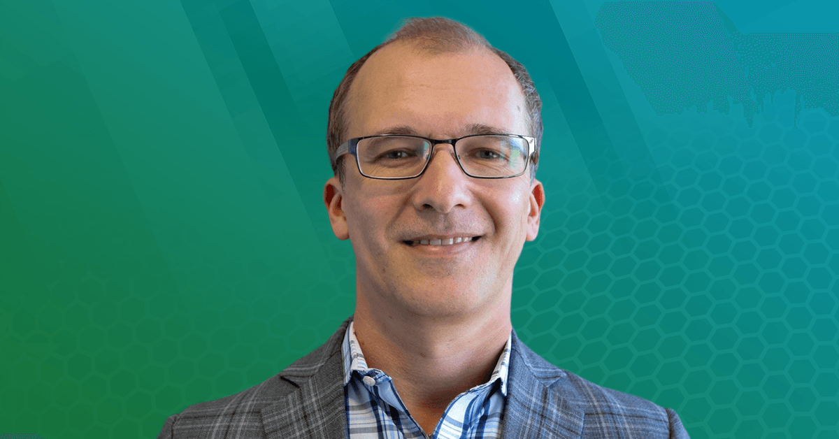A headshot of Prof. Edward F. Valeev, against a blue and green abstract background.