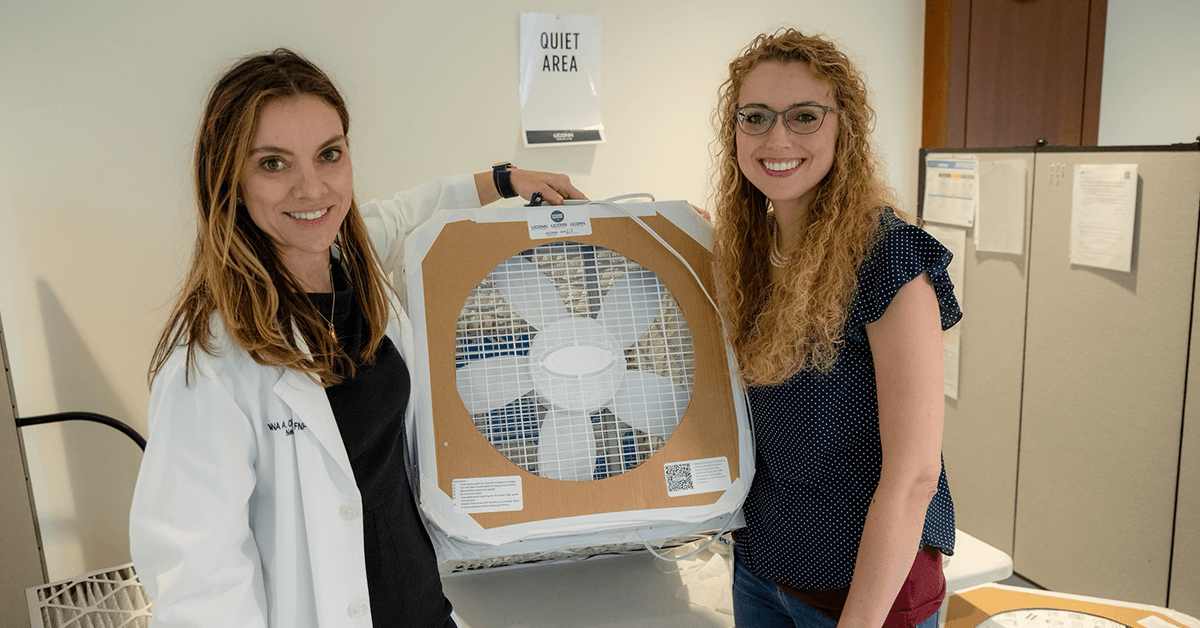Marina Creed, APRN, director of the UConn Indoor Air Quality Initiative (left), and Misti Levy Zamora, assistant professor of public health sciences, hold a DIY Corsi-Rosenthal air filter. (Tina Encarnacion/UConn Health Photo)