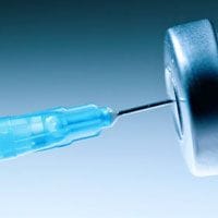 A blue syringe is being inserted into a needle.