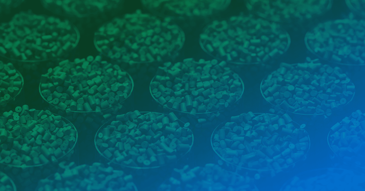 Multiple round trays filled with small, uniformly shaped pellets are arranged in rows under a green and blue lighting.