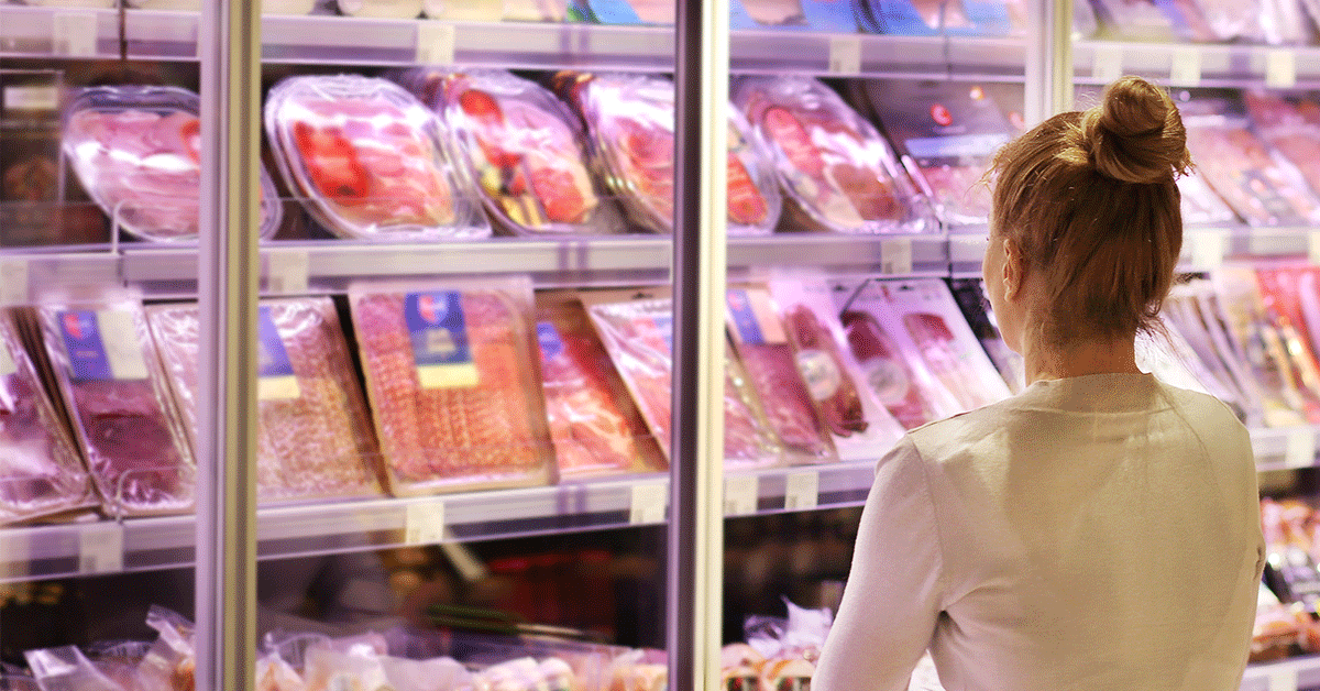 Woman browsing the refrigerated meat section of a grocery store